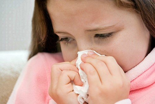 Girl blowing her nose --- Image by © Royalty-Free/Corbis